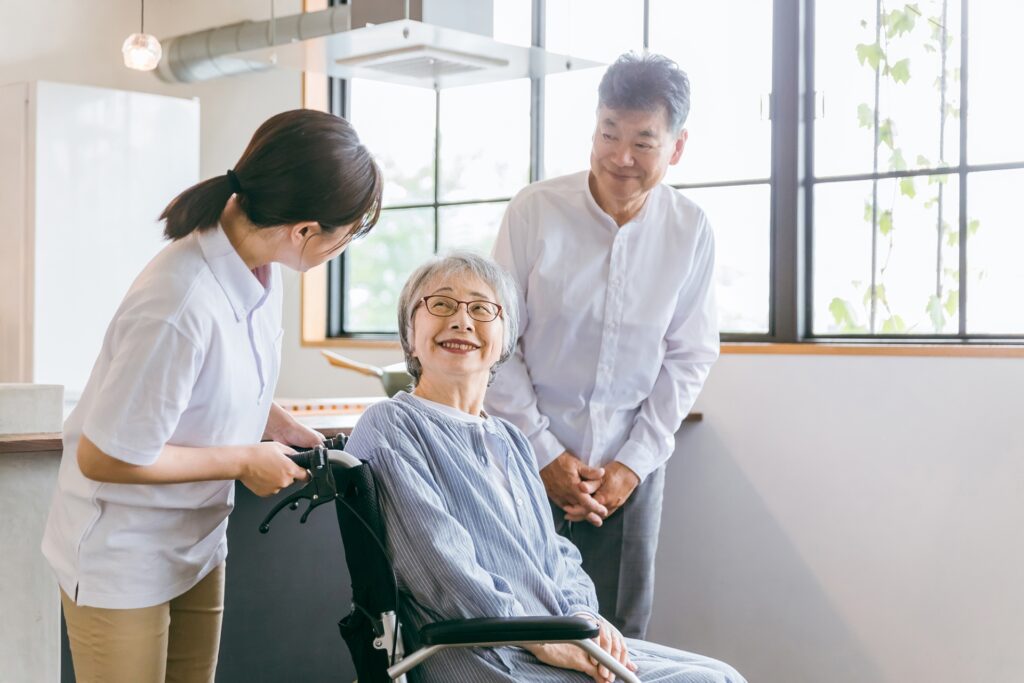 車椅子に座る高齢者夫婦と介護スタッフ
