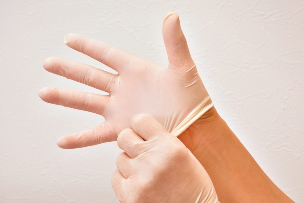 手に手術用の手袋をつける人